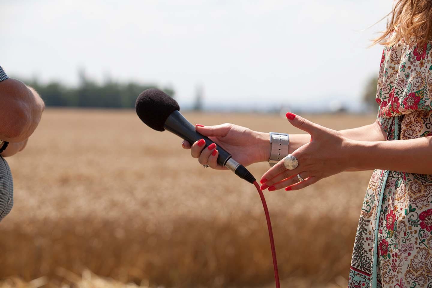 Photo of a person conducting an interview in front of a field