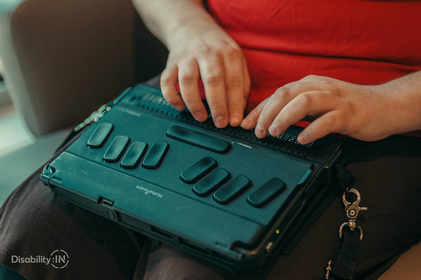 Photograph of a person using a braille-equipped accessibility device. Image credit: Disability:IN and Jordan Nicholson
Licensed under the Creative Commons Attribution-NoDerivatives 4.0 International (CC BY-ND 4.0) license.