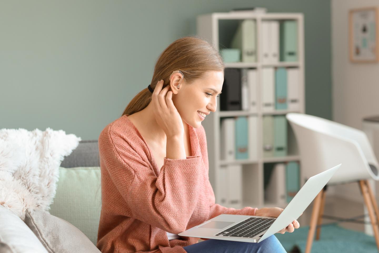 Woman wearing a hearing aid using a laptop